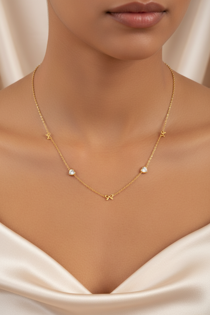 Gold bow and heart necklace on neck