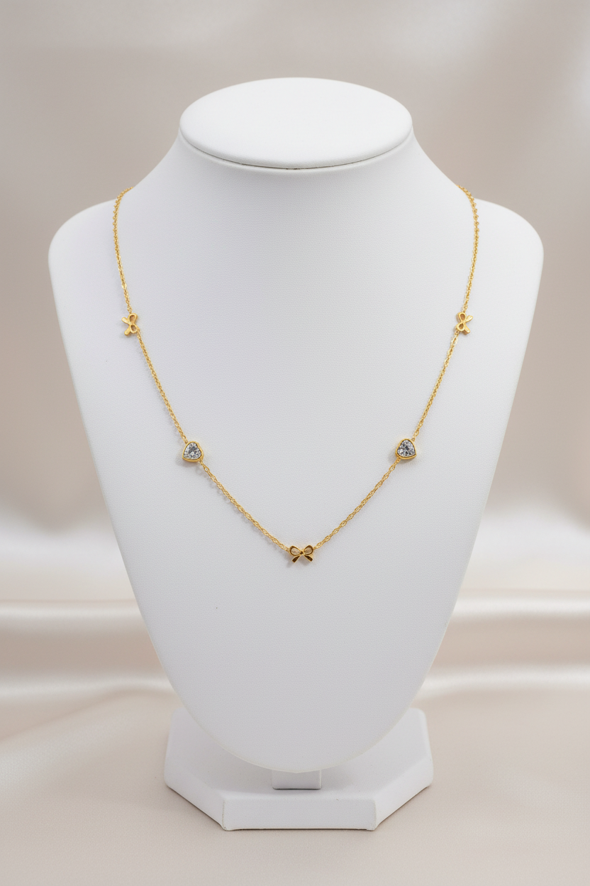 Gold bow and heart necklace on stand