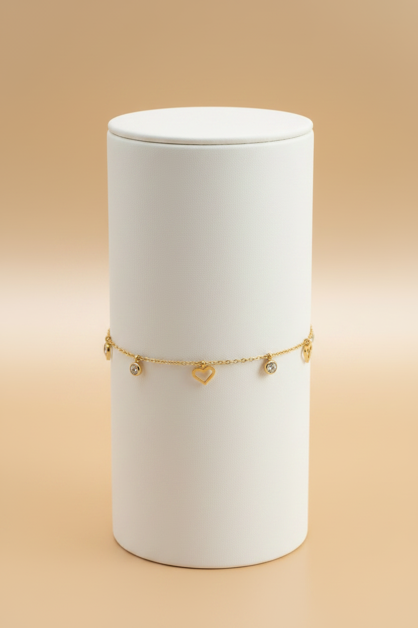 Gold heart charm bracelet on cylindrical stand