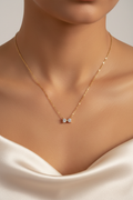 Tiny gold bow necklace on neck