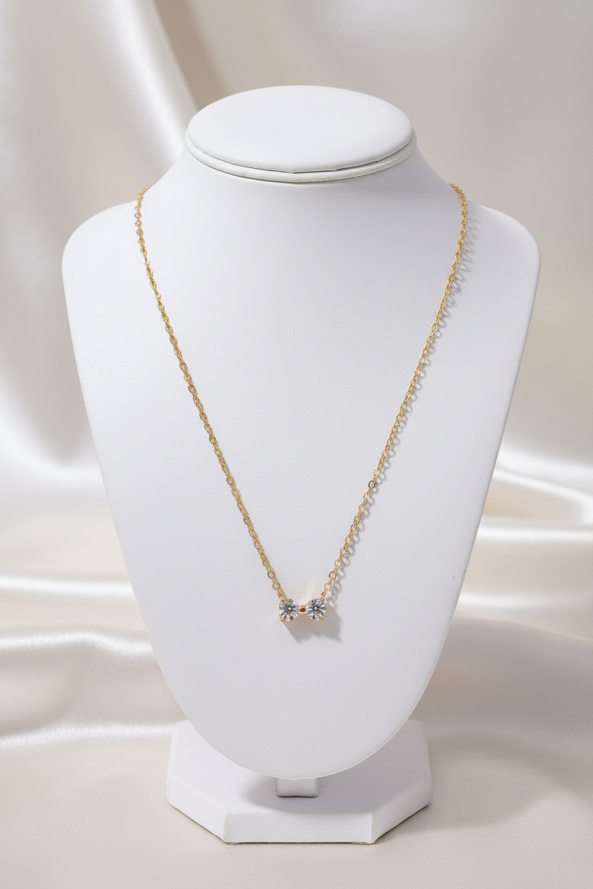 Tiny gold bow necklace on stand